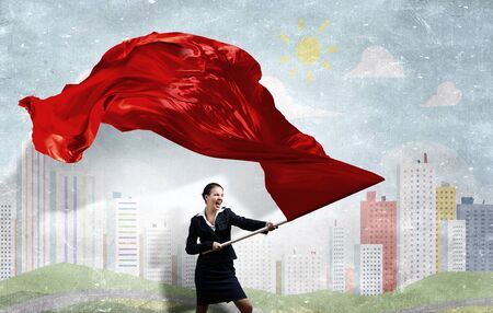 Young determined businesswoman with red flag in handsの写真素材
