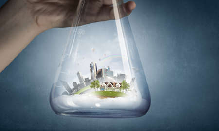 Hand holds flask with image of green life concept