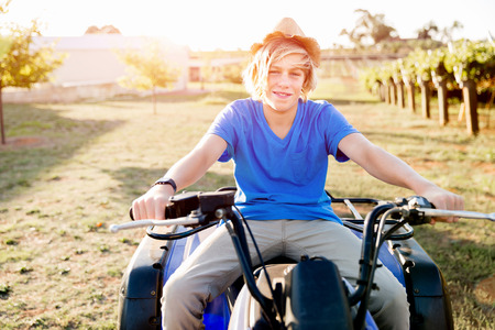Boy wearing hat and riding farm truck in vineyard