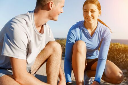 Couple of young runners lace their shoes and prepare to jogging