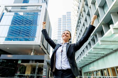 Portrait of young business woman outdoors with arms raised upの写真素材