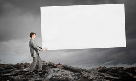 Businessman carrying big blank white banner. Place for textの写真素材