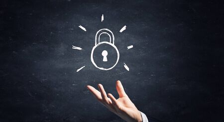 School blackboard and hand with chalk drawing lock on itの写真素材