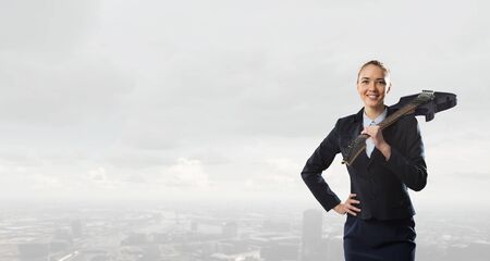 Attractive woman in suit with spread hands and electric guitarの写真素材