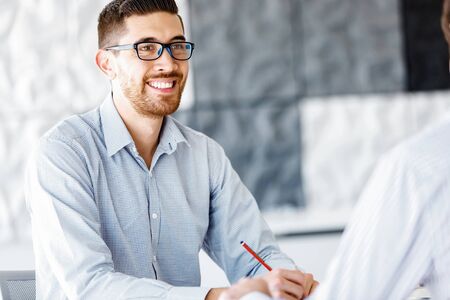 Young businessman sitting at desk in officeの写真素材