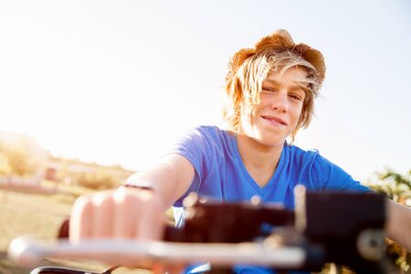Boy wearing hat and riding farm truck in vineyardの写真素材