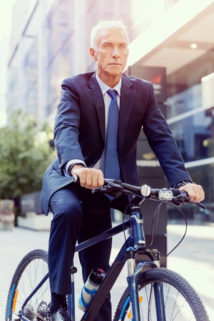 Successful businessman in suit riding bicycleの写真素材