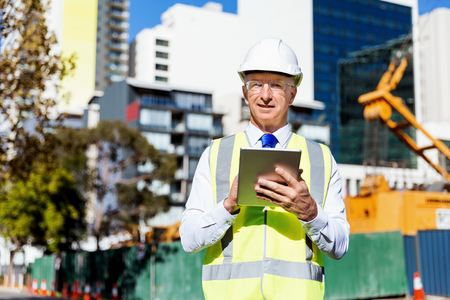 Engineer builder wearing safety vest with notepad at construction siteの写真素材