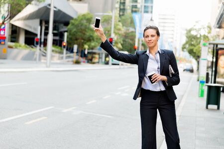Portrait of young business woman catching taxi in cityの写真素材