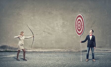 Young woman archer in suit aiming to make shootの写真素材
