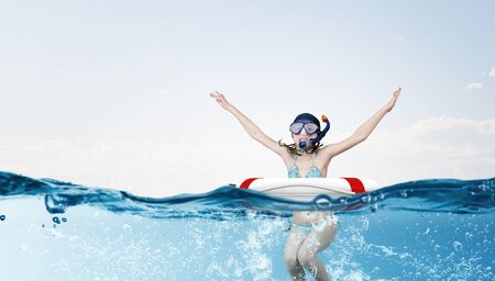 Kid girl of school age in diving mask swimming in life buoyの写真素材