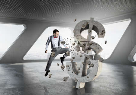 Emotional businessman breaking with anger stone dollar symbolの写真素材
