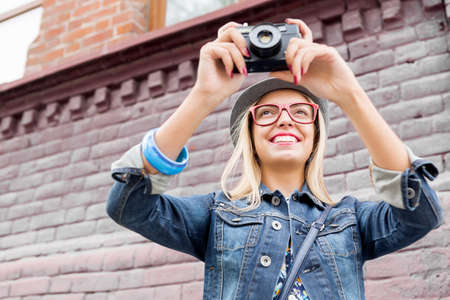 Female young traveler walking on street and taking photo on old cameraの写真素材