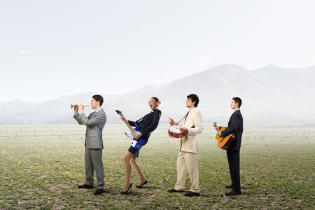 Business people as one team playing different music instrumentsの写真素材