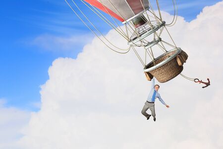 Businessman flying on aerostat balloon high in skyの写真素材