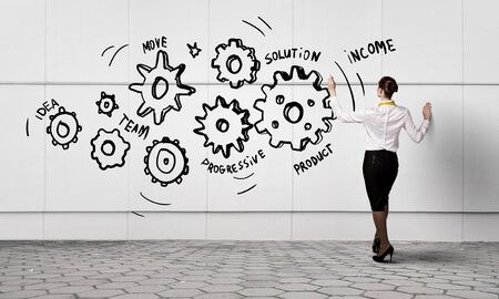 Back view of businesswoman draw gears mechanism on wallの写真素材