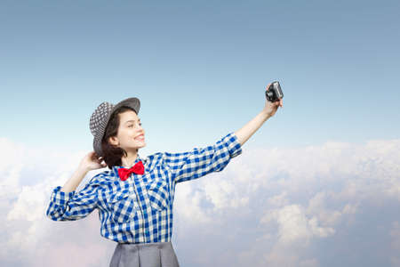 Pretty young girl in casual with retro vintage camera making selfieの写真素材