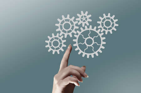 Concept of harmonious working mechanism with finger pointing at gears and cogwheelsの写真素材