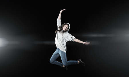 Young woman dancer in jump over dark background