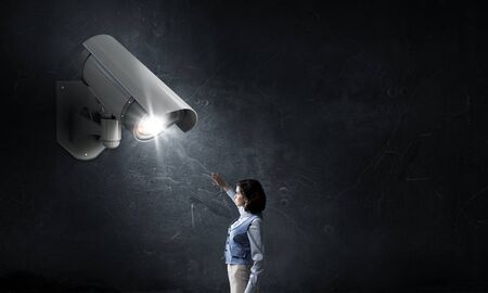 Young woman in room under CCTV camera controlの写真素材