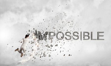 Young emotional woman crashing word impossible with hand punchの写真素材