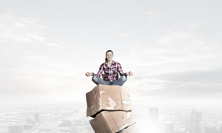 Attractive student girl sitting on stack of carton boxesの写真素材