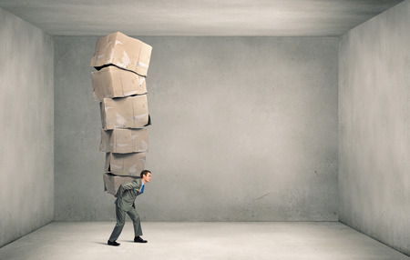 Businessman carrying with effort big stack of carton boxesの写真素材