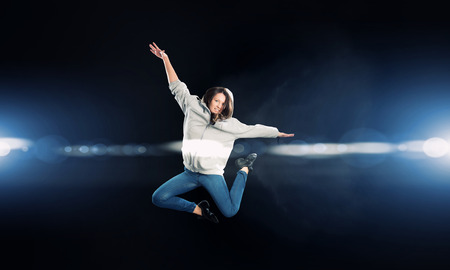 Young woman dancer in jump over dark backgroundの写真素材