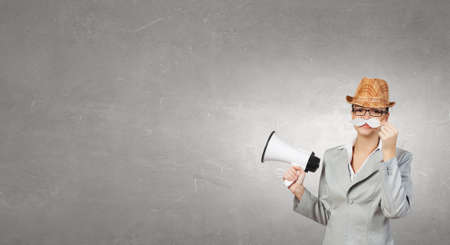 Attractive businesswoman with paper mustache and megaphone in handの写真素材