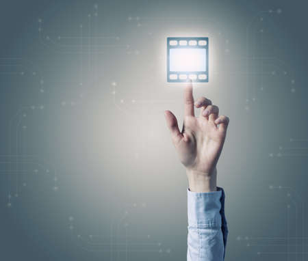 Close up of hand touching video icon on media screenの写真素材