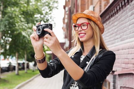 Female young traveler walking on street and taking photo on old cameraの写真素材
