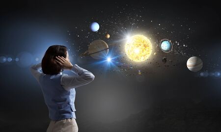 Young woman covering her ears with hands and looking at space planets