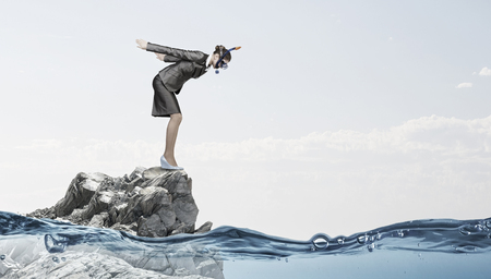 Young businesswoman in suit and mask ready to jump in waterの写真素材