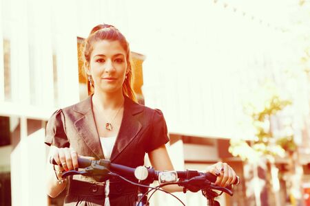 Young woman in business wear commuting on bicycle in cityの写真素材