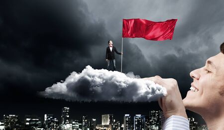 Young man in black jacket holding red waving flagの写真素材
