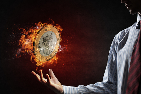 Five euro coin in fire flames in palm on dark backgroundの写真素材