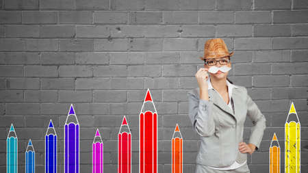 Happy cute girl trying paper mustache to her faceの写真素材