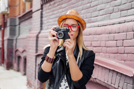 Female young traveler walking on street and taking photo on old camera