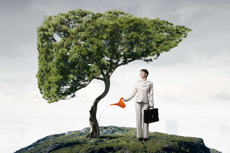 Businesswoman with can watering green growing money treeの写真素材