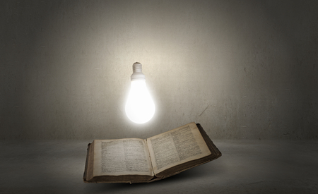 Opened book and glowing light bulb above pagesの写真素材