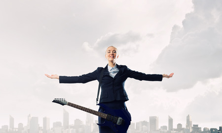 Attractive woman in suit with spread hands and electric guitarの写真素材