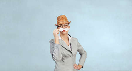 Attractive businesswoman attaching paper mustache to her faceの写真素材