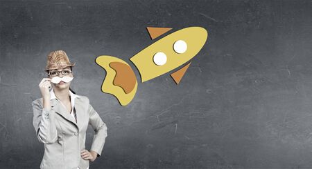 Attractive businesswoman in hat trying on paper mustacheの写真素材