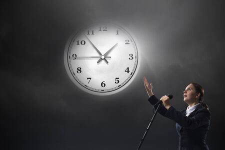 Young businesswoman speaking in microphone on dark backgroundの写真素材