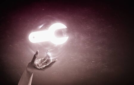 Person hand taking glowing tool sign on blue backgroundの写真素材