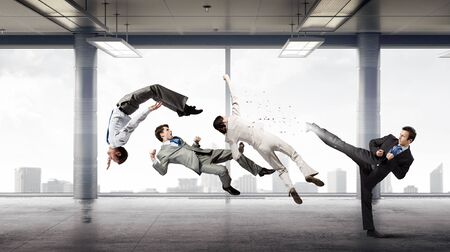 Young determined karate businessman in modern interior fighting with opponent
