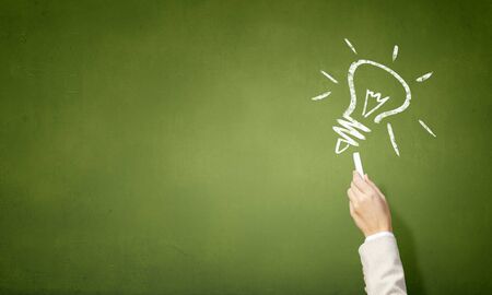 Hand drawing light bulb with chalk on blackboardの写真素材