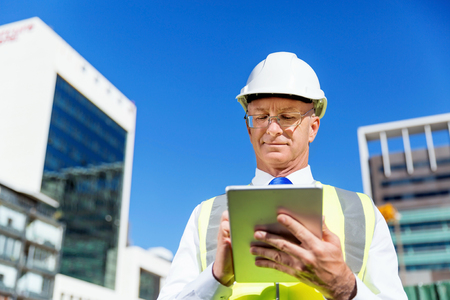 Engineer builder wearing safety vest with notepad at construction siteの写真素材