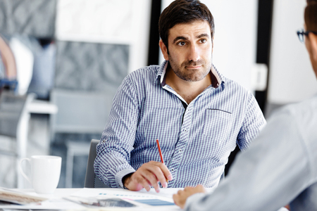 Young businessman sitting at desk in officeの写真素材