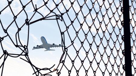 Airplane in mesh of fence taking off from the airportの写真素材